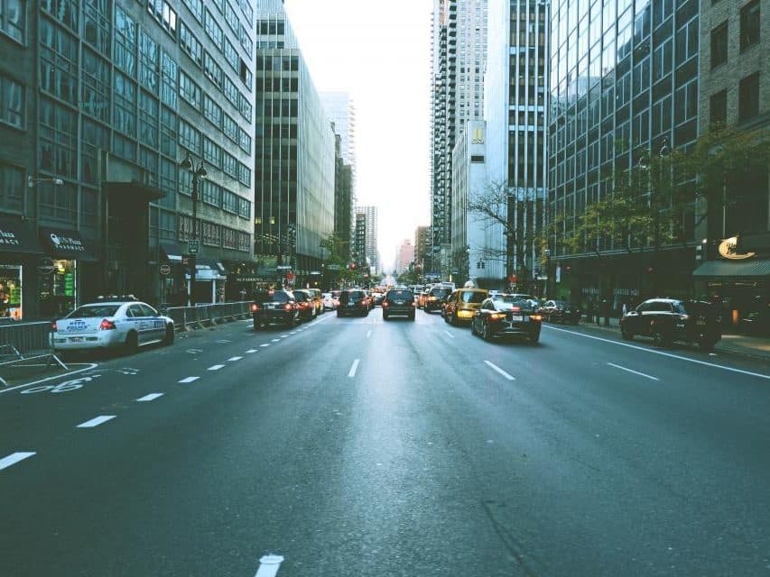 Avenida de una ciudad vista desde el centro de la calzada, con tránsito al fondo