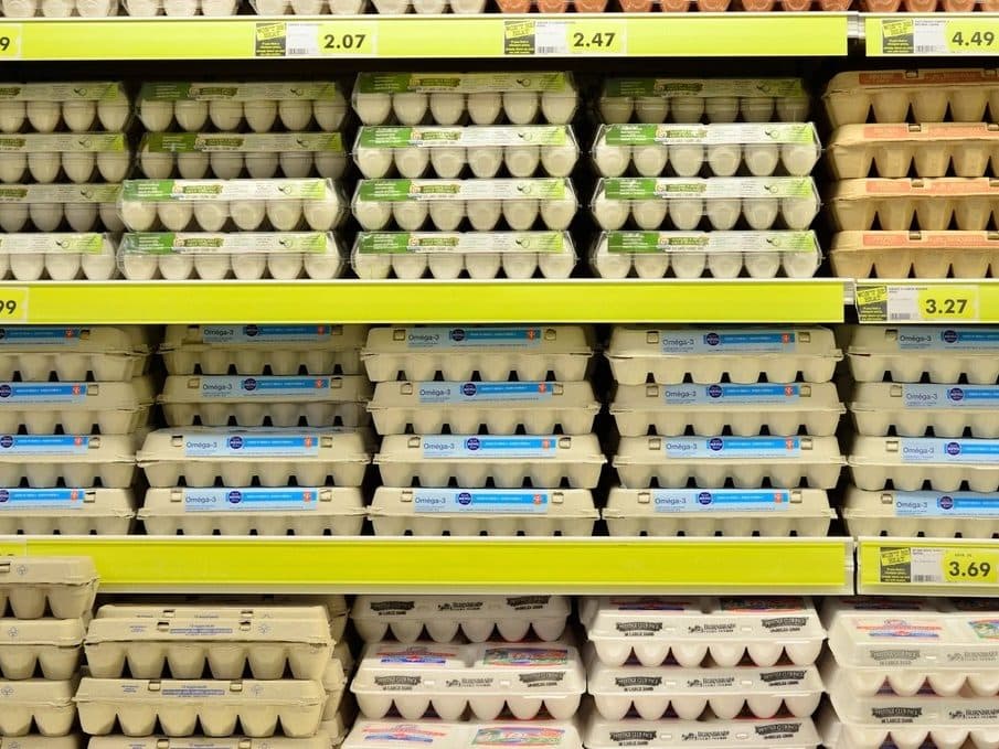 Góndola de supermercado con maples de huevos y tiras de precios